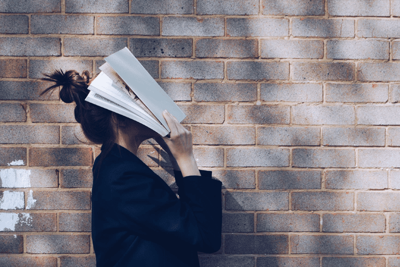 Woman covering her face with books