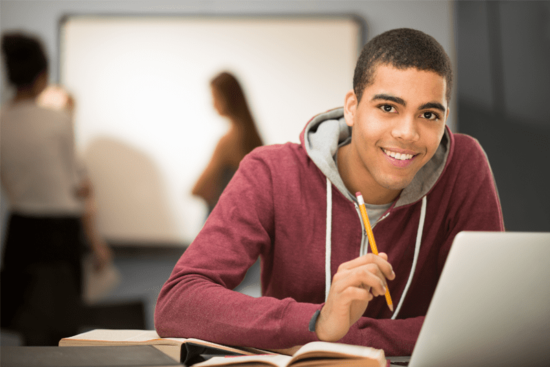 Student smiling in front of a laptop