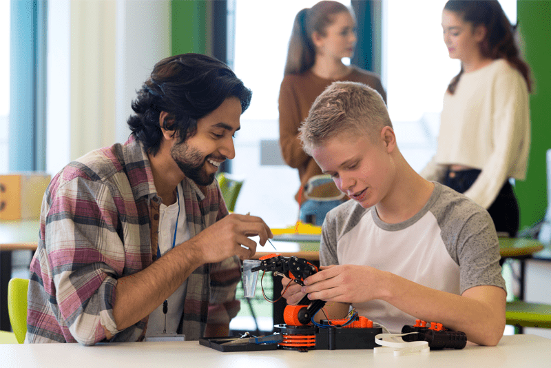 Teacher and student working on a robot