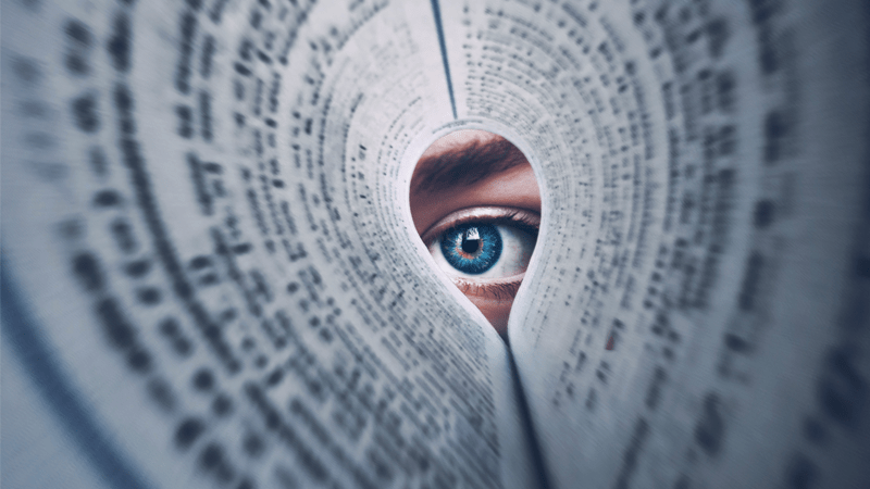 Eye looking through a folded up newspaper