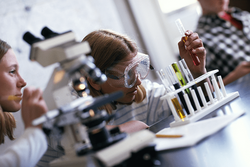 Student with goggles looking at test tubes