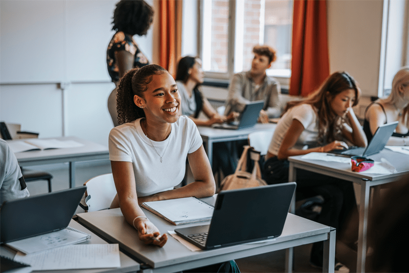 Student sitting at a desk with a laptop smiling