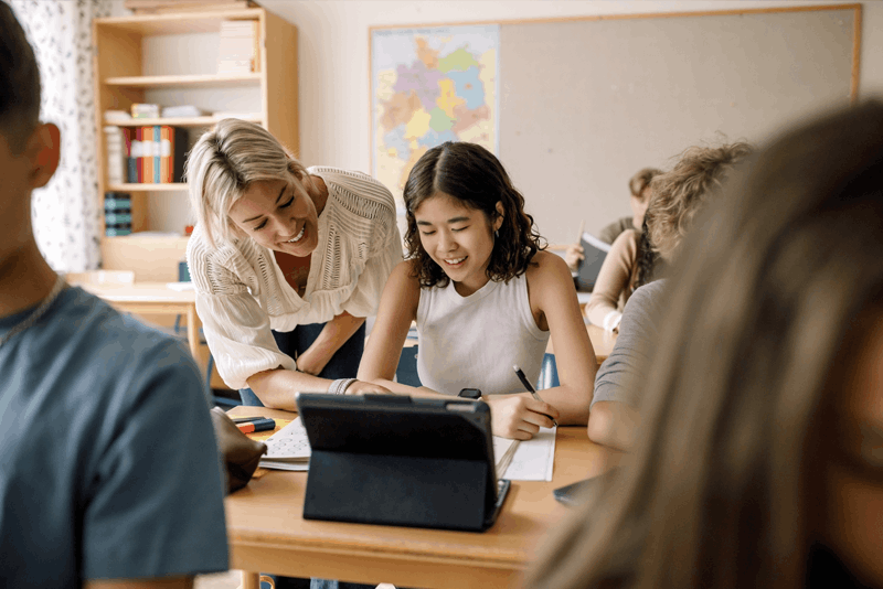Student and teacher smiling in front of a tablet